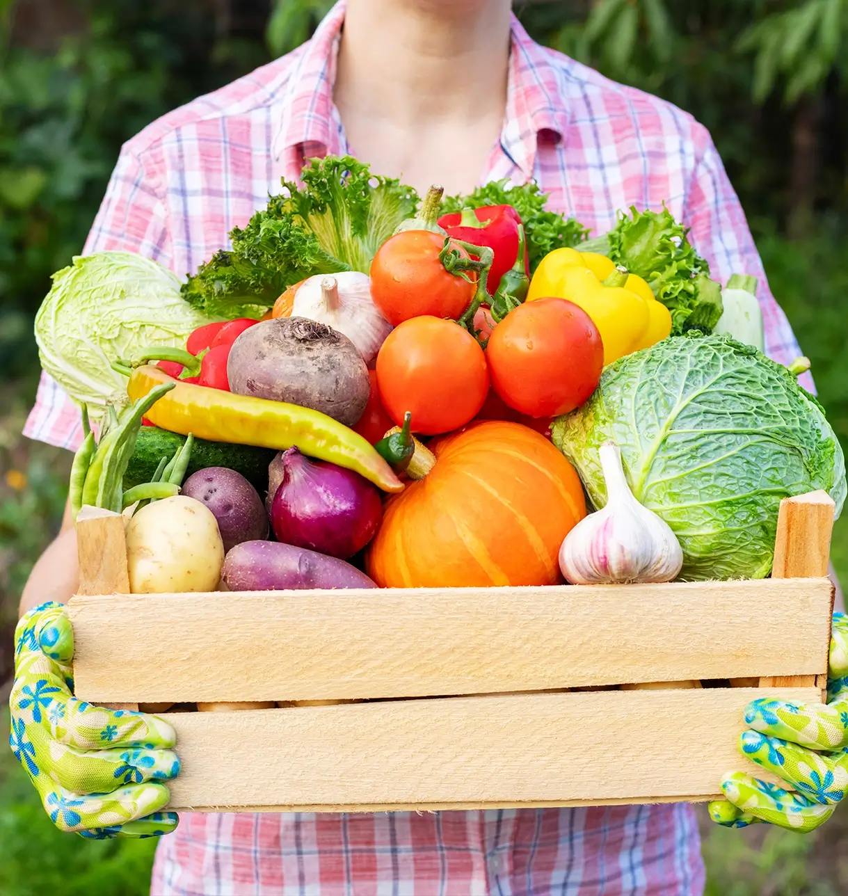 Zoomed in Picture of a worker woman holding a wooden box containing several vegetables sold by Oke produce